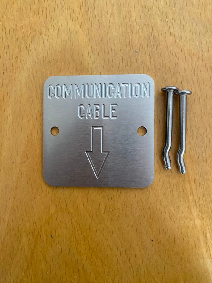 Communication Cable Markers - Engraved identification plates - 'Communication Cables with Arrow Down' (Code; C75-3B). 75 x 75mm by 2mm thick Stainless steel plates. Used by Councils, Communication companies, Civil and utilities. Australian Made. Quality engraved Stainless steel plates / markers - 75 x 75mm by 2mm thick. Includes a 5 x 50mm Stainless steel mushroom head fixing spike, (for Wet or Dry concrete).